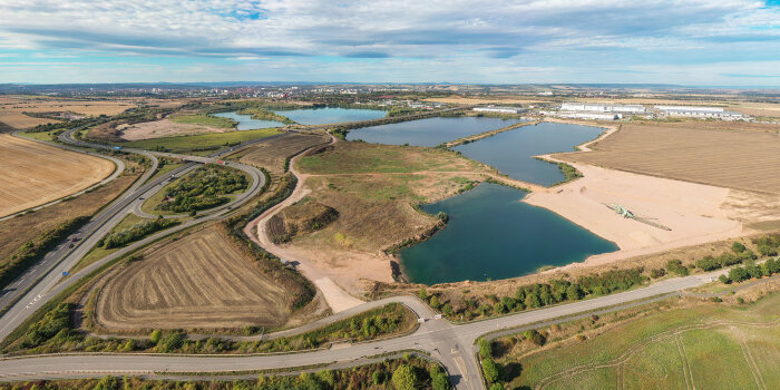 Luftaufnahme einer Landschaft mit mehreren See, die in flache Felder eingebetten und von Straßen umgeben sind