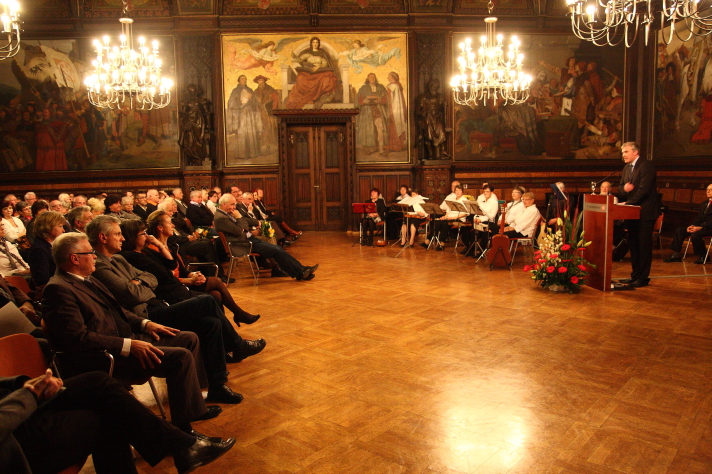 Oberbürgermeister am Rednerpult vor Publikum im Rathausfestsaal.