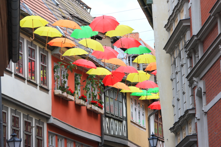 Ein buntes Dach aus Schirmen über einer Altstadtgasse.