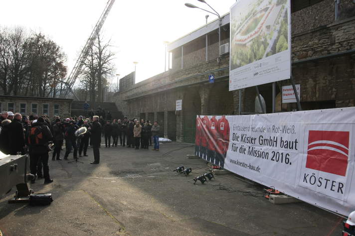 Gäste und Offizielle unter dem Bauschild zum neuen Stadion.
