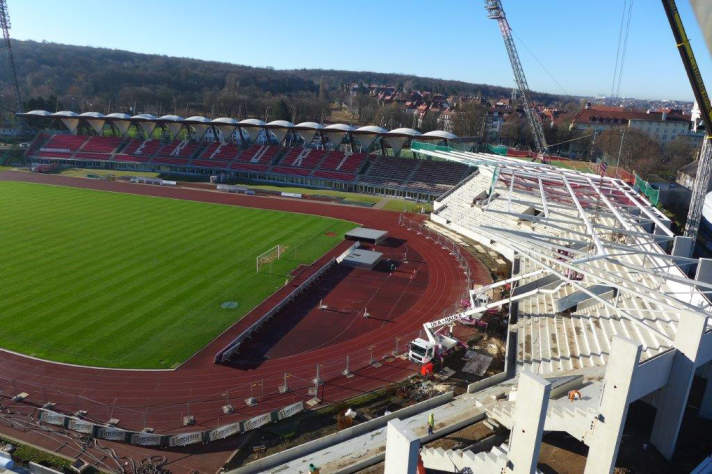 Stadionbaustelle mit Tribünen im Rohbau, Montage der Dachkontruktion.