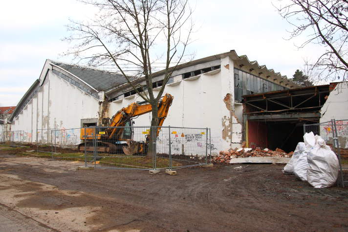 Abrissbagger bei der Arbeit an großer Sporthalle