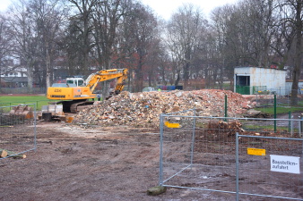 Abrissbagger vor einem Berg von Bauschutt.