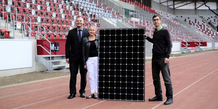 Drei Personen präsentieren ein Solarmodul