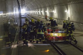Rettungskräfte stehen vor dem Zug und schaffen eine Trage hinein, im Hintergrund liegt bereits ein Verletzter auf einer Trage.