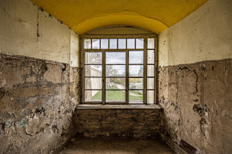 Blick durch altes Fester, eingerahmt von Festungsmauern mit bröckeligen Wänden