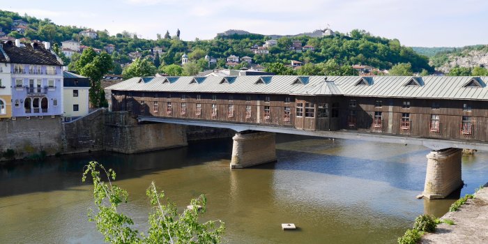 Eine mit Häusern bebaute Brücke vor einer grünen Landschaft.