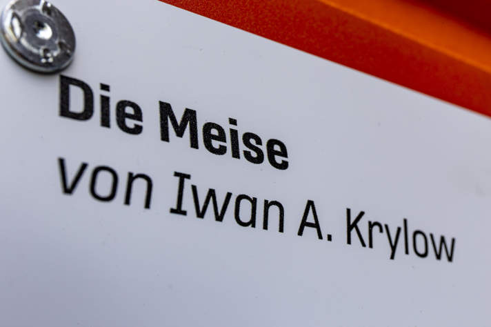Text "Die Meise, von Iwan A. Krylow" auf einem weißen Infoschild.