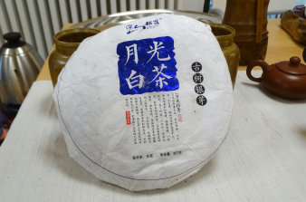 Verpackter chinesischer Tee in der Form eines weißen Fladenbrotes, versehen mit chinesischen Schriftzeichen.