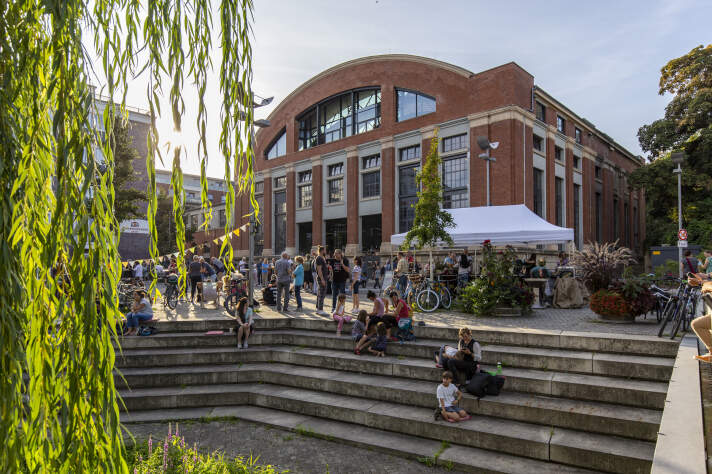 Straßenfest vor einem großen Backsteingebäude am Abend.