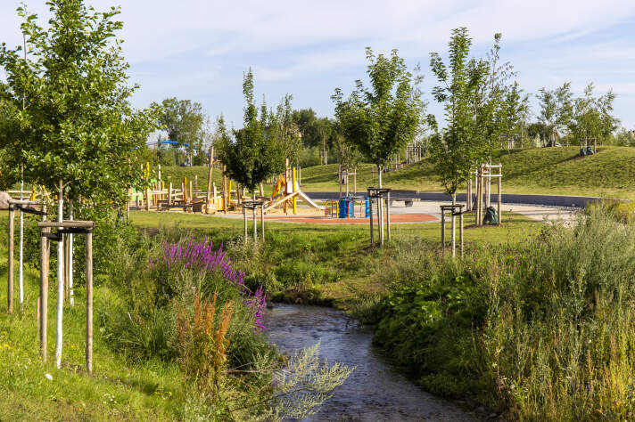 ein Bach in eine Parklandschaft mit einem Spielplatz