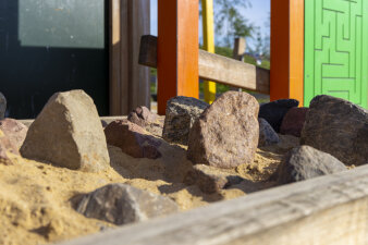 ein Behältnis mit Sand und Steinen auf einem Spielplatz