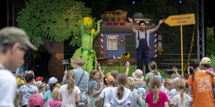 Kinder vor einer Bühne, auf der ein Kinderstück gespielt wird