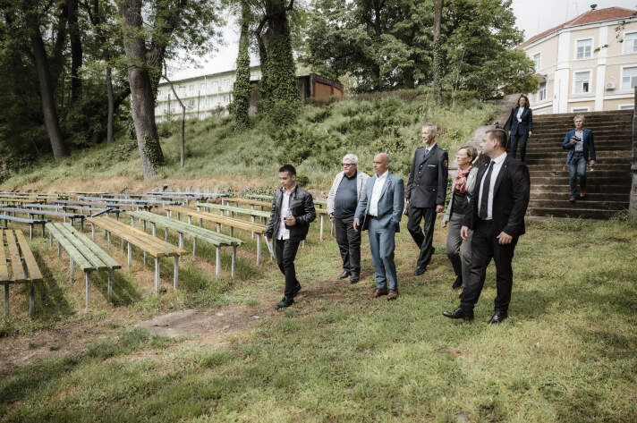 eine Gruppe von Menschen geht einen begrünten Hügel hinunter, auf dem Sitzbänke stehen
