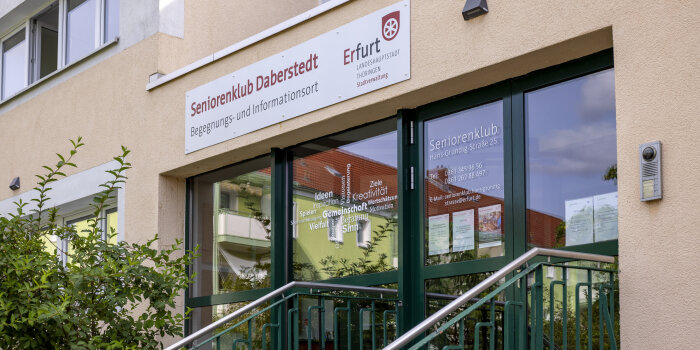 Der Eingang in ein Gebäude. Die Treppe hat ein grünes Geländer und über der Tür steht: Seniorenklub Daberstedt.