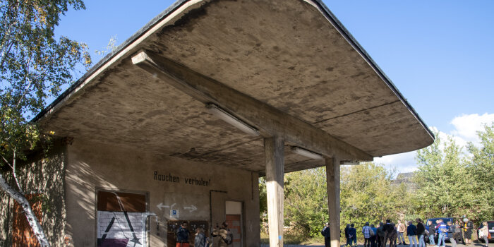 Fassade einer alten Tankstelle mit Menschen davor