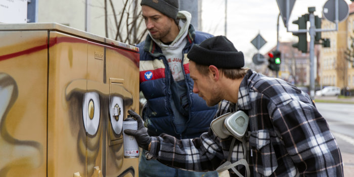Zwei junge Künstler sprühen "Bernd das Brot" als Motiv auf einen Steuerungsschrank einer Ampel.