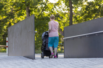eine Frau mit Kinderwagen läuft über eine Rampe in einem Park