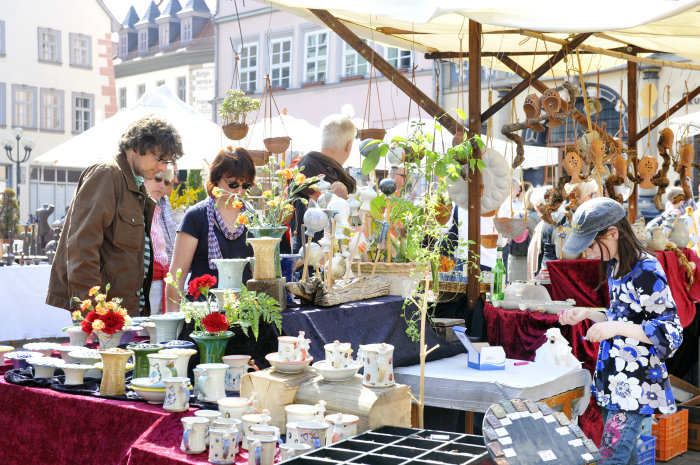 Menschen auf einem Marktplatz betrachten Töpferwaren