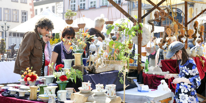 Menschen auf einem Marktplatz betrachten Töpferwaren