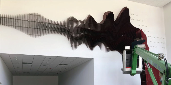 Foto: Montage der Zuschauerwelle im Steigerwaldstadion © Stephan Scharlach Tiefrote Metalllamellen werden an eine Wand montiert.
