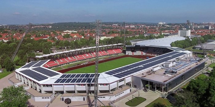 Ein Stadion mit einem angrenzenden Gebäude aus der Vogelperspektive aufgenommen