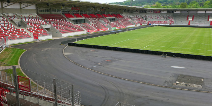 Ein Stadion, in dem die Tartanbahn erneuert wird und gerade nur der Asphalt zu sehen ist. 