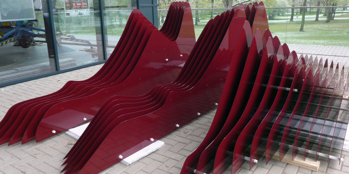 Eine Kunstwerk aus vielen roten Metallteilen, die zusammen eine Welle ergeben.