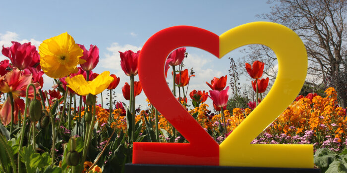 Das Logo zum Tag der Deutschen Einheit - eine herzförmige 22 - vor Tulpen, Mohn und anderen Blumen.