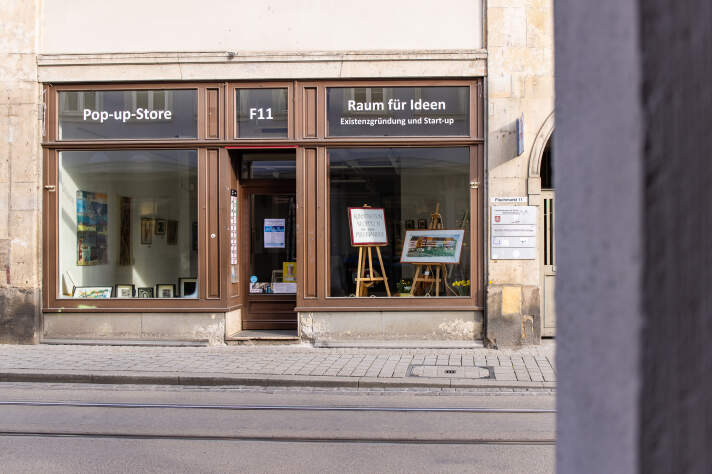 Schaufenster eines Ladens, in dem sich verschiedene Werke in Rahmen befinden