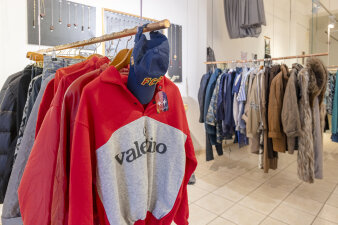auf mehreren Kleiderstangen hängen Kleidungsstücke, im Vordergrund ein Pullover mit valentino-Aufdruck