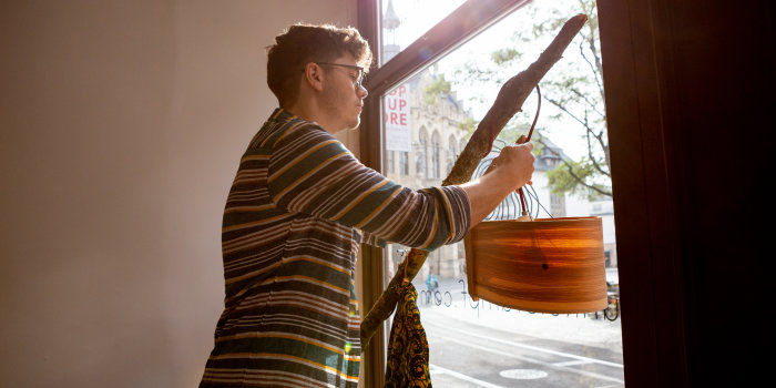 Ein Mann hängt in einem Schaufenster eine Lampe auf. 