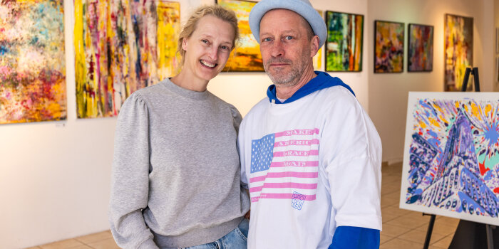Ein Mann und eine Frau stehen in einem Rasum voller Kunstwerke. 
