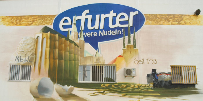 gemaltes Bild an der Fassade der Erfurter Teigwaren GmbH mit Dom und Severi, Mehl, einem aufgeschlagenen Ei, verschiedenen Nudelsorten und dem Logo des Unternehmens
