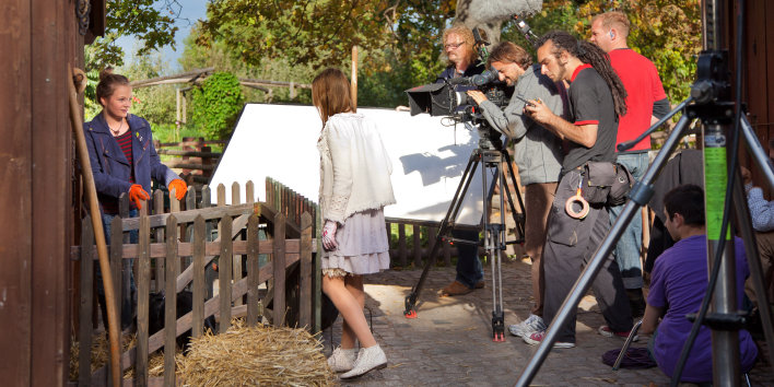 Zwei Mädchen vor einer Scheune von einem Kamerateam gefilmt