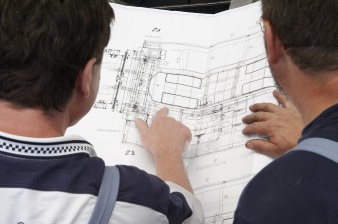 Zwei Arbeiter sehen sich den Konstruktionsplan einer Maschine an