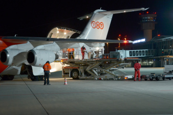 Bei Nacht wird das Frachtflugzeug von TNT über einen Hubwagen beladen