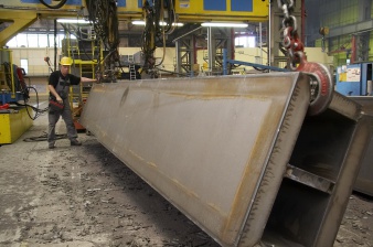 Arbeiter richtet meterlanges Metallteil mit Kran auf