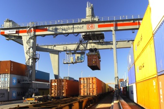 Umschlagterminal im Erfurter Güterverkehrszentrum. Ein Brückenkran lädt Container von einem Güterzug auf einen Lkw um. Viele weitere Container rechts und links warten auf die Abfertigung.