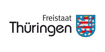 Das Logo zeigt rechts das Wappen Thüringens, einen rot-weiß gestreiften Löwen mit Krone auf blauem Grund, links daneben den Schriftzug "Freistaat Thüringen" in schwarzer Schrift auf weißem Grund.