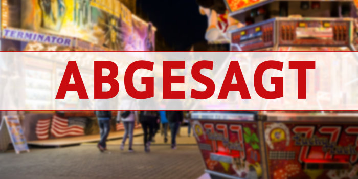 Veranstaltung abgesagt Im Hintergrund: ein Rummel, nachts, unscharf, im Vordergrund ein Banner mit der Aufschrift „abgesagt“