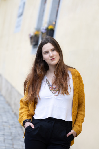Eine Frau steht vor einem Gebäude und schaut in die Kamera.