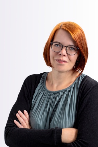 Jessika Zitzmann Eine Frau mit roten Haaren und Brille schaut in die Kamera.