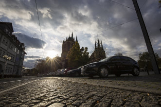 Straße mit Kopfsteinpflaster, parkende Autos, im Hintergrund der Dom