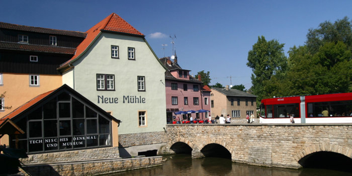 Gebäude einer Mühle am Fluss mit Brücke.