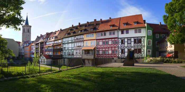 mit Häusern bebaute Brücke aus sieben Bögen über einem Fluss; Sichtfenster zur Mikwe im Vordergrund