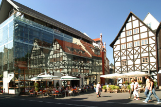 Benediktsplatz mit moderner Glasfassade, in der sich mittelalterliche Fachwerkhäuser spiegeln.