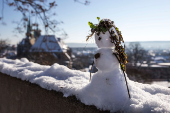 Schneemann Petersberg Im Vordergrund zu sehen ist ein kleiner Schneemann auf einem Mauersims des Petersberges, im Hintergrund ein Blick über die Stadt und den Dom.