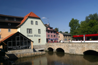 Gebäude einer Mühle am Fluss mit Brücke.