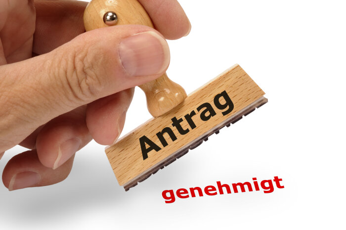Stempel: Antrag genehmigt Stempel in der Hand mit Aufschrift Antrag genehmigt